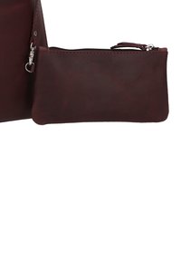 Borsa a mano in cuoio marrone con una piccola tasca con zip staccabile. Texture liscia, design minimalista e dettagli in metallo argentato.