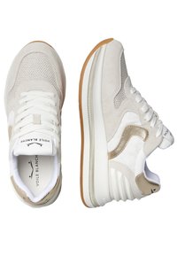 Zapatillas de color claro con una combinación de ante y malla. Presentan elementos texturizados, cordones blancos y una suela de goma. La marca es visible en la lengüeta.