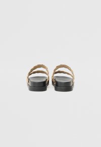 Sorte sandaler med to flettede gullstropper. Flat såle med en jevn overflate. Minimalistisk design, passende for hverdagsbruk.