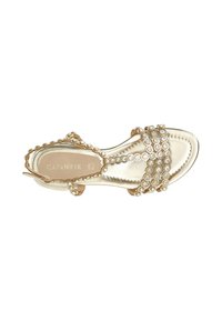 Guldmetallisk sandal med flera remmar prydda med cirkulära stenar som liknar ädelstenar. Slät textur och platt sula, öppen tådesign.
