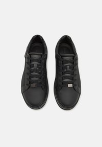 Black leather sneakers with rounded toes, textured side panels, evenly spaced laces, and a subtle logo accent on the tongue.