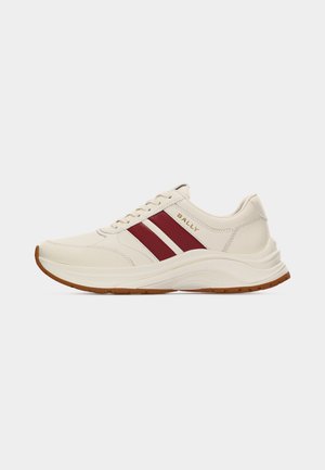 Zapatilla de cuero color crema con dos franjas rojas en los costados, logo dorado "BALLY", suela blanca y dibujo marrón en la banda de rodadura, vista de perfil izquierdo.