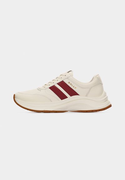 Baskets en cuir couleur crème avec deux bandes latérales rouges, logo "BALLY" doré, semelle blanche et bande de roulement marron, vues de profil gauche.