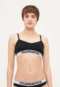 Fekete sportmelltartó állítható pántokkal, széles rugalmas szalaggal, rajta fehér "Fila" logóval. Simás textúra, minimális varrás.