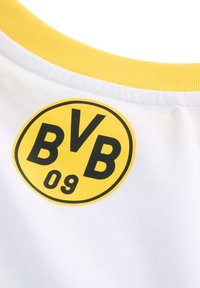 Hvidt stof med en gul ribbet krave. Har et cirkulært sort logo med "BVB" og "09" i midten. Enkel og ren design.