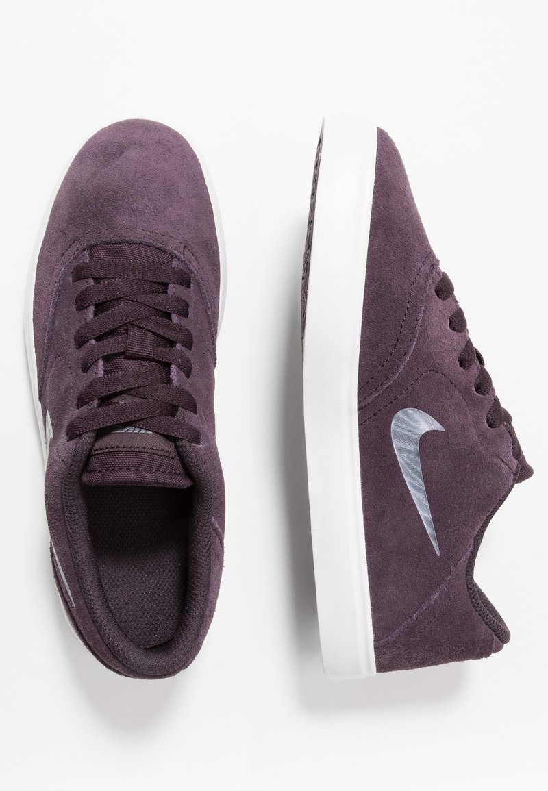 Paire de baskets Nike en daim violet foncé avec semelles blanches, l’une vue de dessus lacée, l’autre vue de côté avec le logo argenté Nike swoosh.