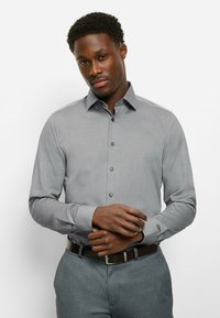 Gray, button-up shirt with a subtle textured pattern, long sleeves, and a pointed collar. Black buttons and a tailored fit.