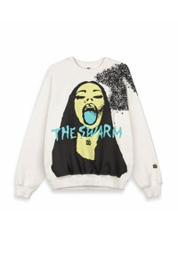 Witte sweatshirt met een afbeelding van een vrouw met een gele gezicht, open mond, blauwe tong, zwart haar, een zwarte zwerm op haar schouder, en teal tekst "DE ZWERM."