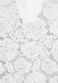 Tissu en dentelle blanche présentant des motifs floraux, des détails complexes et un fond en maille fine, créant une texture et un design délicats.