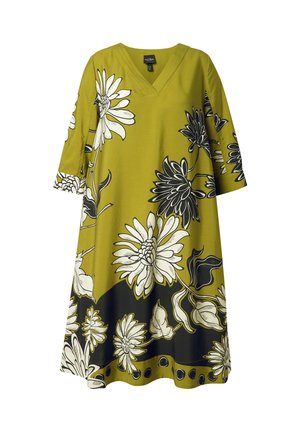 Groene midi-jurk met V-hals en driekwart mouwen, met grote witte en zwarte bloemenpatronen en zwarte accenten bij de zoom.