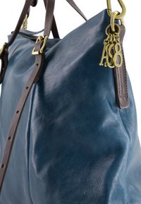 Lederhandtasche in Tiefblau, mit strukturiertem Oberflächen, braunen Trägern, Messingbeschlägen und einem Anhänger mit den Buchstaben "A8."