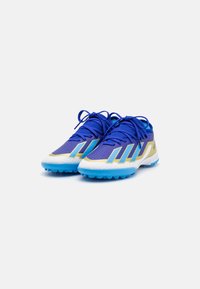 Scarpe da ginnastica blu dal design elegante, con materiale bianco perforato, accenti gialli e suola blu texturizzata per una migliore aderenza.