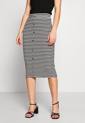 Woman wearing a black sleeveless top and a black-and-white horizontal striped midi skirt with front buttons and black heeled sandals.