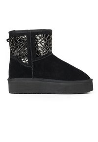 Bota de tobillo de ante negro con una suela de goma plana, que presenta un diseño decorativo con recortes y acentos de tachuelas en el panel lateral.
