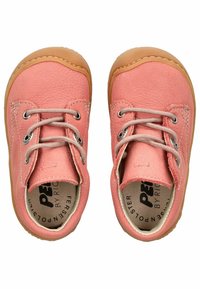 Un paio di scarpe per bambini in pelle rosa con suole di gomma color carne, dotate di due passanti, lacci e un collare imbottito.