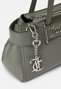 Grøn, tekstureret, syntetisk håndtaske med sølv hardware, der har en dekorativ kæde og et stiliseret logo-charm fastgjort på siden.