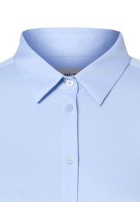 Jasnoniebieska koszulka polo z klasycznym kołnierzykiem, z plisą na guziki i gładkim, lekkim materiałem. Prosty, jednolity kolor bez wzorów.