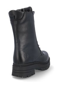 Bota de tobillo de cuero negro con una textura suave, punta redondeada y suela gruesa de goma con dibujo para mayor tracción. La parte trasera tiene un detalle de marca mínimo.