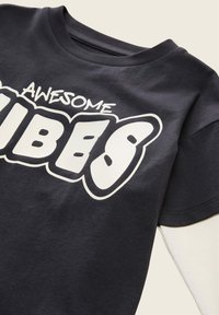 T-shirt grigio scuro con testo stampato bianco "AWESOME VIBES." Maniche corte, collo tondo, in tessuto di cotone, texture liscia, vestibilità comoda.