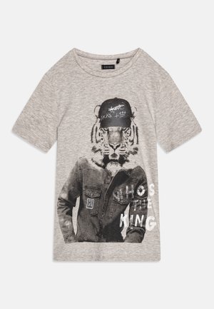 Jasnoszara koszulka z grafiką tygrysa w czapce i kurtce, z częściowo widocznym napisem "KTO JEST KRÓLEM."