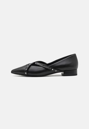 Chaussure plate noire à bout pointu avec un petit talon et des brides croisées décoratives ornées de petits rivets argentés.
