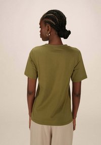 T-shirt olive vert à manches courtes avec un col rond, fabriqué à partir d'un tissu doux, présentant une coupe décontractée et un ourlet standard.