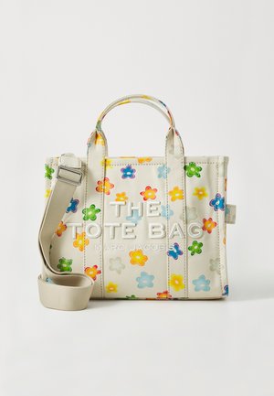 Liten totebag i lys beige stoff med fargerike blomstertrykk. Har doble topphåndtak og en avtakbar, justerbar skulderrem.