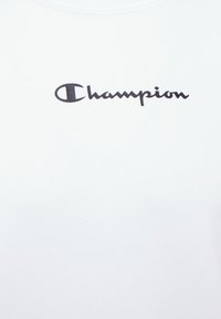 Witte katoen t-shirt met een ronde hals, voorzien van een opvallend zwart "Champion" logo over de borst in cursieve lettertype.