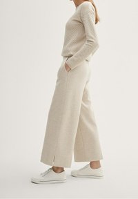 Beige strukturerad tröja med långa ärmar, tillsammans med ljusbeige vida byxor med sidofickor. Kompletterad med vita sneakers.