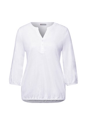 Blouse blanche pour femme avec manches trois-quarts, col en V à trois boutons, et ourlet élastique, présentée sur un fond blanc.