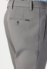 Pantalons gris ajustés avec une coupe slim, une taille plate à l'avant et une poche arrière avec un bouton et un détail d'étiquette. Texture de tissu lisse.