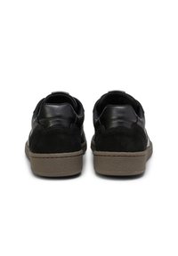 Schwarze Leder- und Wildledersneaker mit einer strukturierten grauen Gummisohle, die ein glattes Finish und eine abgerundete Fersenkurve aufweisen.