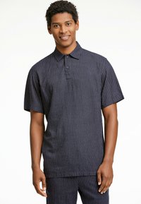 Marinrandig polo shirt med korta ärmar, krage och treknappslåst. Tillverkad av andningsbart tyg med en slät yta.
