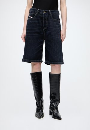 Persoon die een zwart mouwloos topje draagt, donkere denim kniebroek en glanzende zwarte kniehoge laarzen met hak.