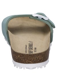 Scarpa verde in pelle senza lacci con una soletta in sughero, suola esterna bianca con battistrada e dettagli in hardware argentato. L'interno presenta una fodera beige e il marchio.