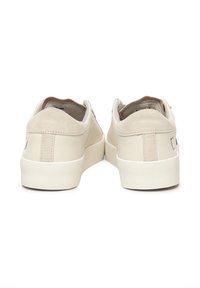 Baskets en cuir beige avec une finition lisse, à profil bas et semelle en caoutchouc blanc texturé. La vue arrière montre un design minimaliste et un détail de marque.