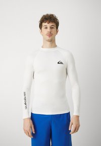 Biała koszulka ochronna z długim rękawem, wykonana z elastycznego materiału, z czarnym logo na piersi i napisem "Quiksilver" na rękawie.