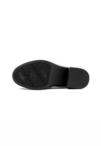 Semelle de chaussure habillée noire avec motifs de grip texturés et talon bloc, présentée sur un fond blanc.