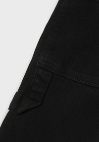Tejido de mezclilla negra con una textura suave, forma recta, detalle de bolsillo y sutiles acentos de costura a lo largo de los bordes.