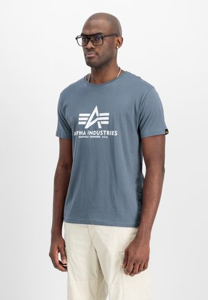 Grijze katoenen T-shirt met een witte grafische logo "ALPHA INDUSTRIES" op de voorkant, korte mouwen en een ronde halslijn met een rechte zoom.