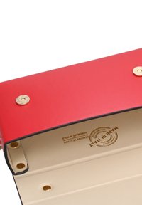 Portafoglio rosso in pelle con dettagli in metallo dorato, caratterizzato da una texture liscia e un interno beige. Logo inciso "Made in Italy" visibile all'interno.