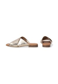 Metallic gold slip-on sandals with a crossed strap design, flat wooden heel, and a smooth leather texture.