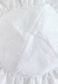 Abito bianco con intricate decorazioni ricamate caratterizzate da motivi floreali e dettagli simili al pizzo, vita arricciata e una morbida trama di cotone.
