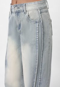 Ljus tvättade denimbyxor med en lös passform. Har hög midja, framfickor och synliga sömnadsdetaljer längs sidorna.