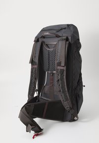 Schwarzer Rucksack mit gepolstertem, belüftetem Rückenteil, verstellbaren Trägern und elastischen Akzenten. Funktionales Design mit mehreren Befestigungspunkten.