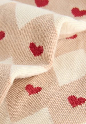 Knit fabric featuring a beige and cream checkered design with red heart patterns. Soft texture, lightweight appearance.