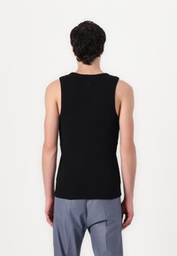 Zwarte mouwloze tanktop met een ronde hals, een getailleerd ontwerp, gemaakt van gladde stof; heeft geen zichtbare logo's of patronen.