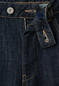 Blugi din denim închis au un design clasic, cu elemente din alamă pentru nasturi, cusături portocalii în contrast și fermoar. Material texturat cu țesătură vizibilă.
