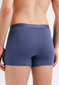 Navy blue boxer shorts with a smooth, stretchy fabric. Features a soft waistband with subtle branding. Cut for a fitted shape.