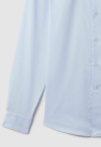 Chemise à manches longues bleu clair en tissu lisse, dotée d'un col boutonné à l'avant et de poignets classiques avec de subtils détails de couture.